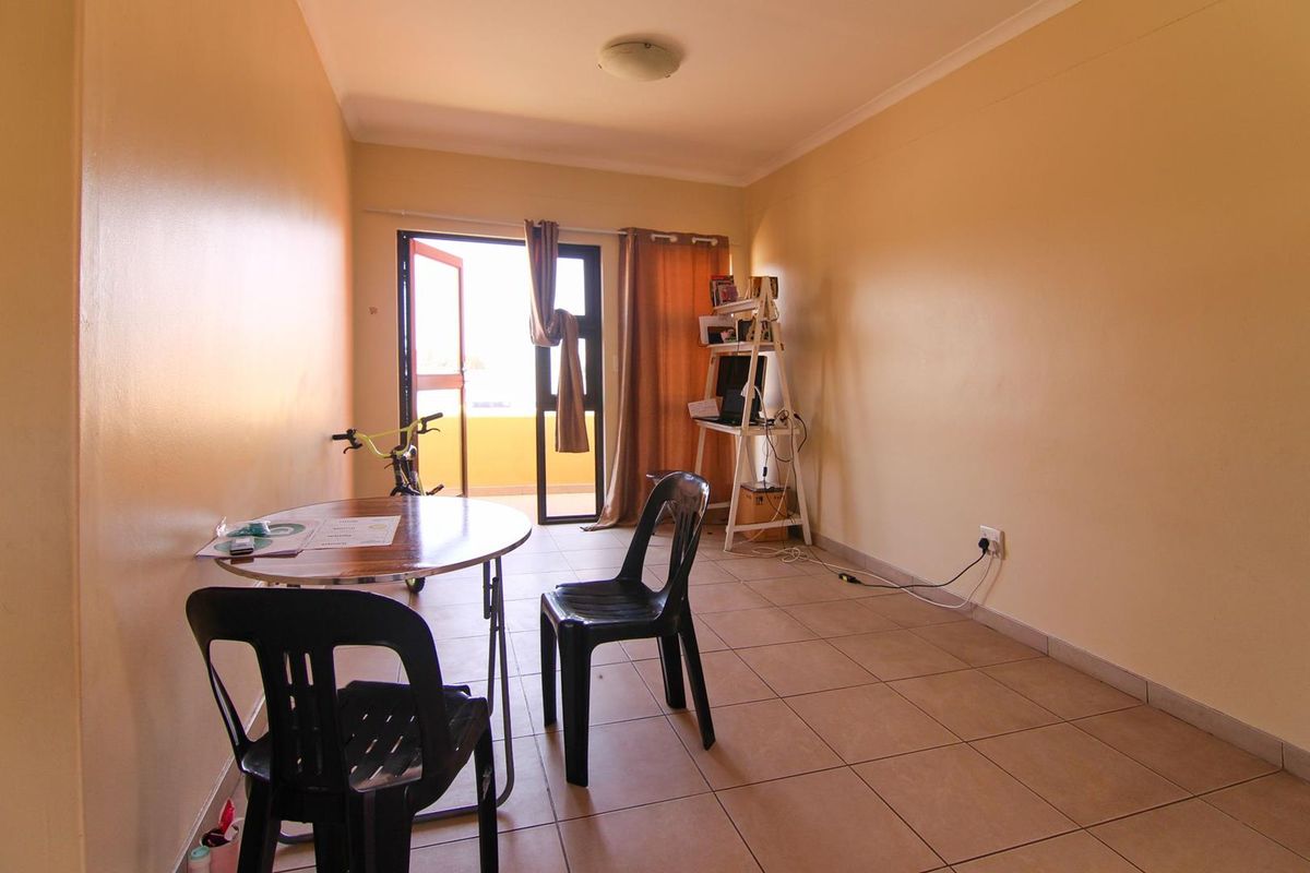 A simple living area featuring tiled flooring and a glass door providing access to an outdoor balcony space.