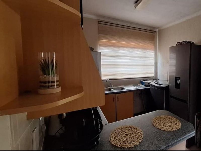 A functional kitchen featuring laminate cabinetry, a stainless steel sink, and a breakfast bar counter, offering a practical layout for daily use.