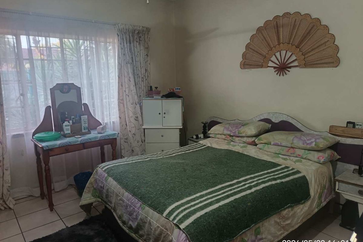 A bedroom featuring tiled flooring, a wall-mounted air conditioning unit, and large windows with curtains.