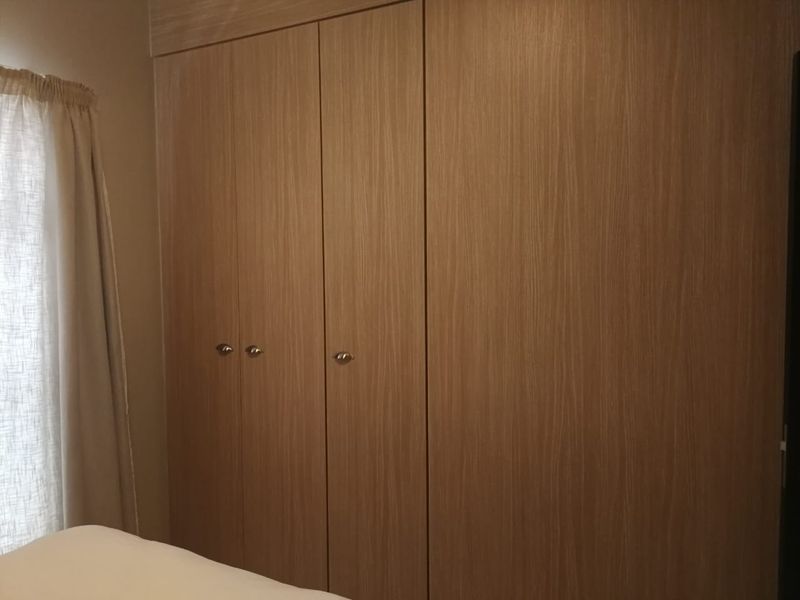 A bedroom featuring a large, modern built-in wardrobe with wood-grain finish doors.
