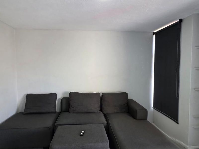 A simple living room featuring a roller blind and built-in wall shelving, providing a neutral base for personalization.