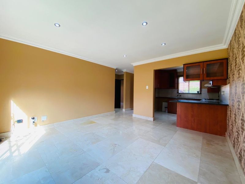 Open plan living area featuring stone tile flooring, recessed lighting, and an adjoining kitchen with built-in cabinetry and a breakfast counter.