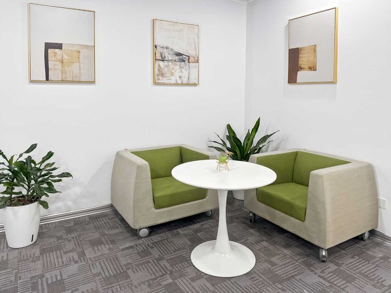 A clean and well-maintained office breakout area featuring neutral walls, carpeted flooring, and modern finishes.