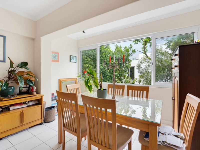 Bright dining area featuring large sliding windows that provide ample natural light and pleasant views of the surrounding greenery.
