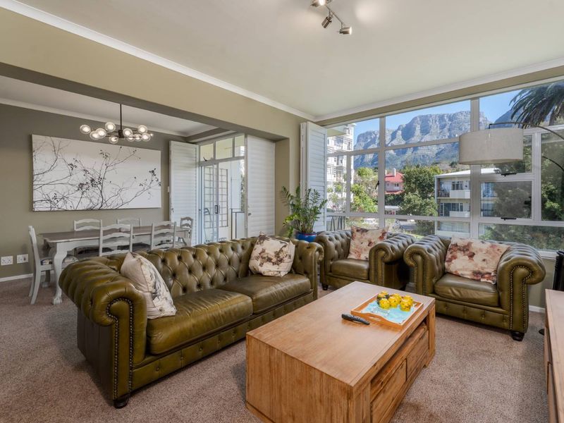 Spacious open-plan living and dining area featuring large windows with mountain views and plantation shutters, creating a bright and inviting atmosphere.