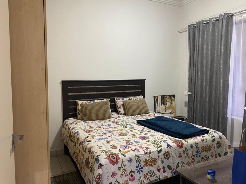 A functional bedroom featuring a built-in wardrobe and window with curtain rod, providing a comfortable and practical living space.