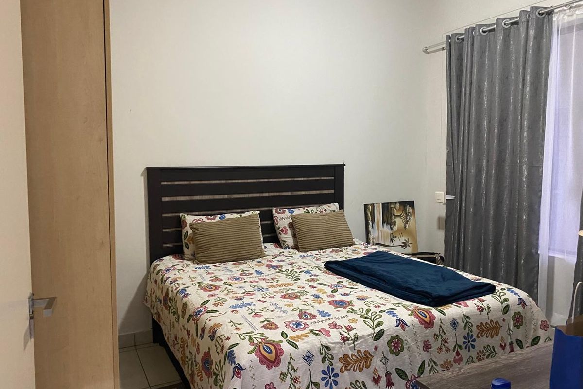 A functional bedroom featuring a built-in wardrobe and window with curtain rod, providing a comfortable and practical living space.