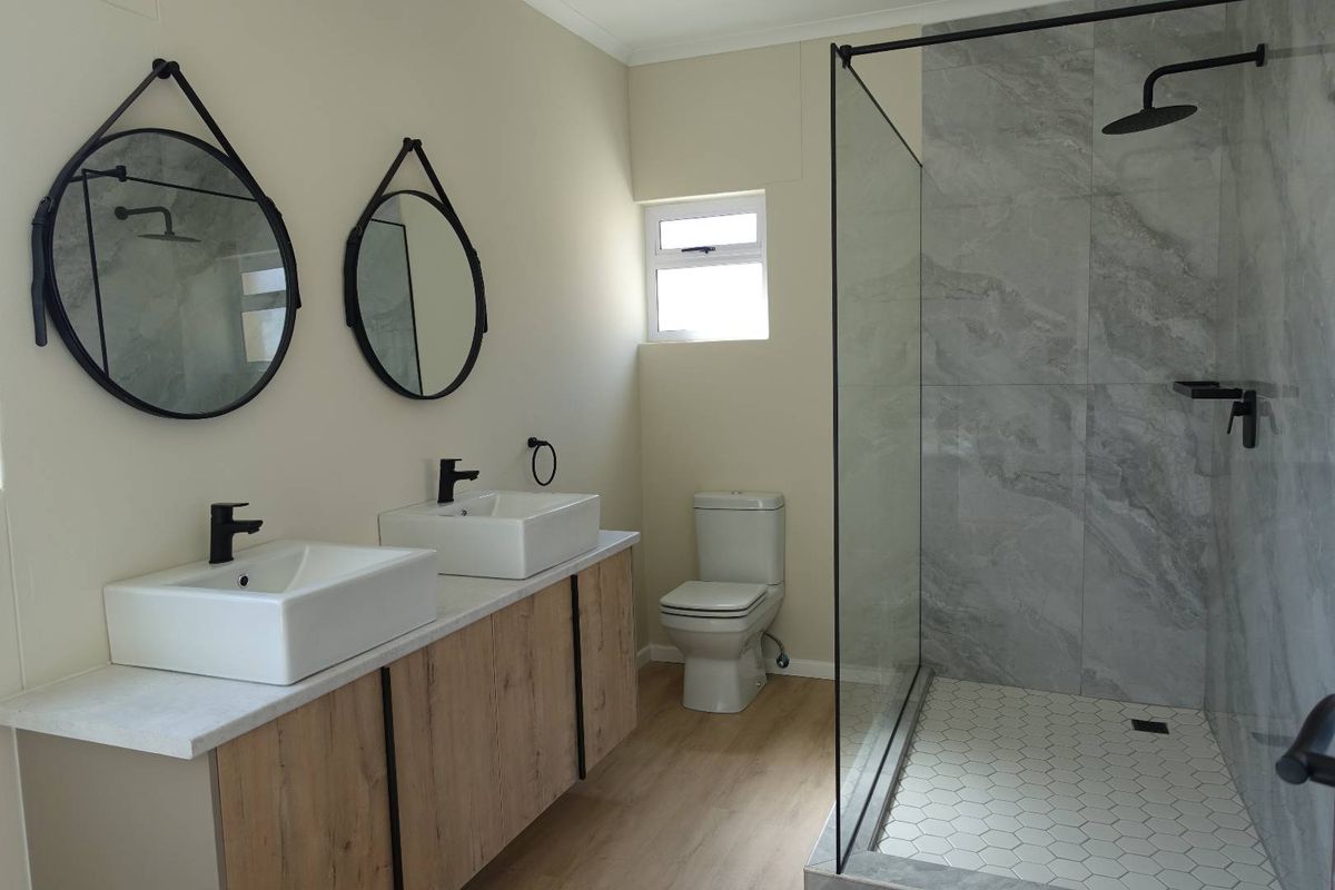 Modern bathroom featuring a double vanity with vessel sinks, a spacious walk-in shower with glass screen, and contemporary finishes throughout.