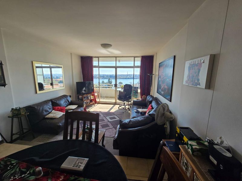 A comfortable living room featuring large sliding glass doors that provide natural light and access to a balcony with scenic water views.