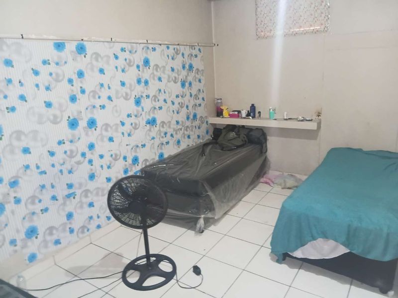 A bedroom featuring tiled flooring and a built-in wall shelf, currently requiring cosmetic updates to improve its overall aesthetic appeal.