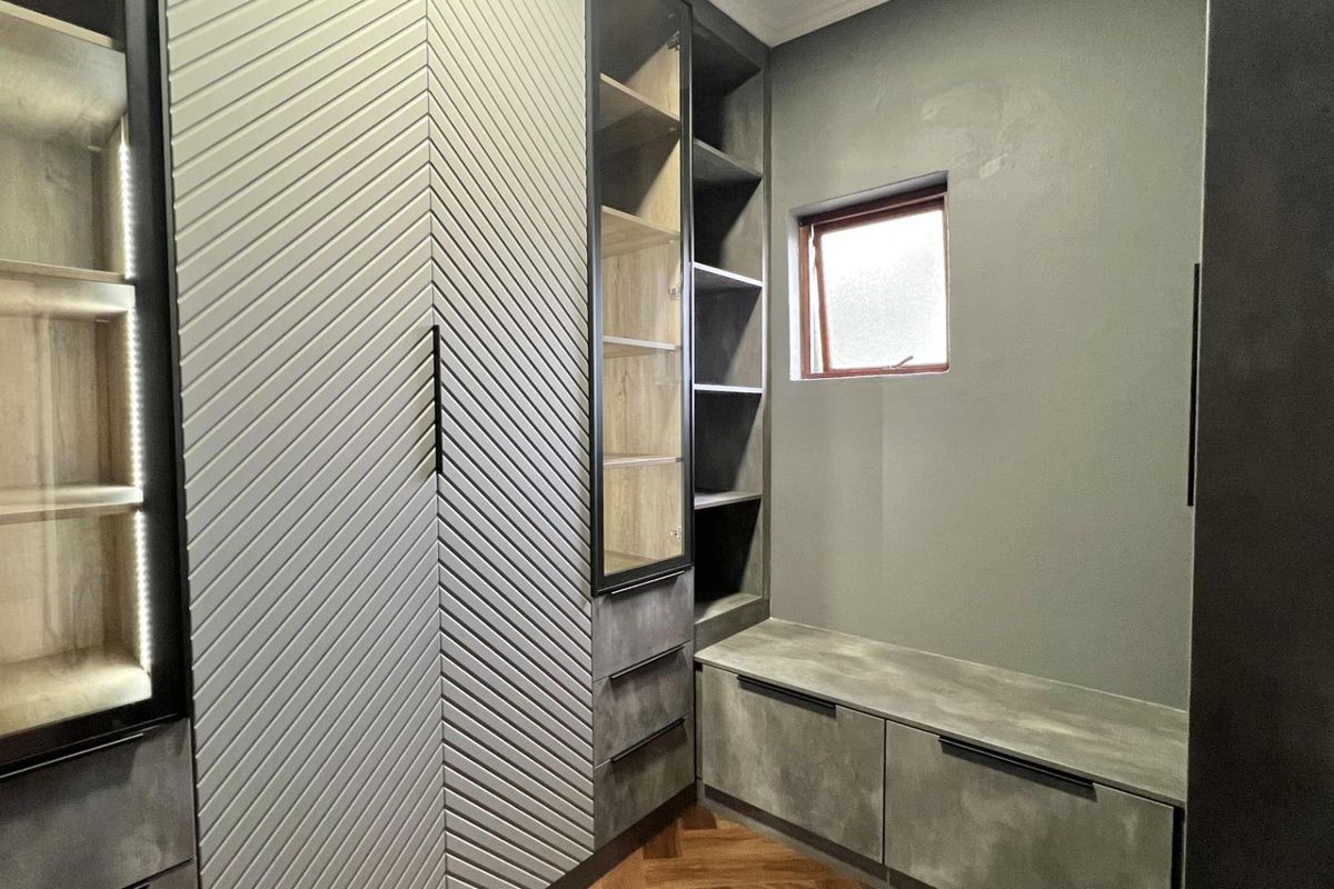 A modern, custom-fitted dressing room or walk-in closet featuring textured cabinetry, integrated shelving, and a built-in bench seat with storage.