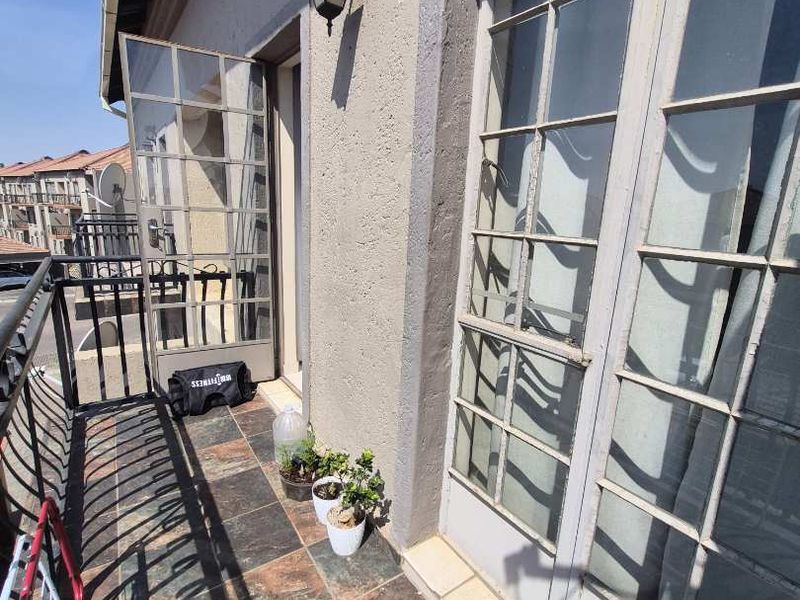 A balcony area featuring tiled flooring, metal balustrades, and multiple sets of french doors providing access to the apartment interior.