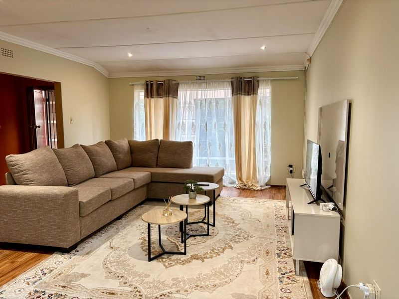A comfortable living room featuring laminate flooring, coved ceilings with recessed lighting, and a large sliding glass door providing natural light.