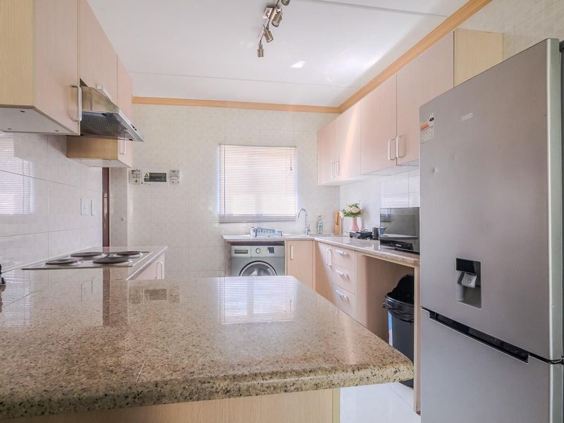 Functional kitchen featuring granite countertops, ample built-in cabinetry, a tiled backsplash, and integrated plumbing for laundry appliances.