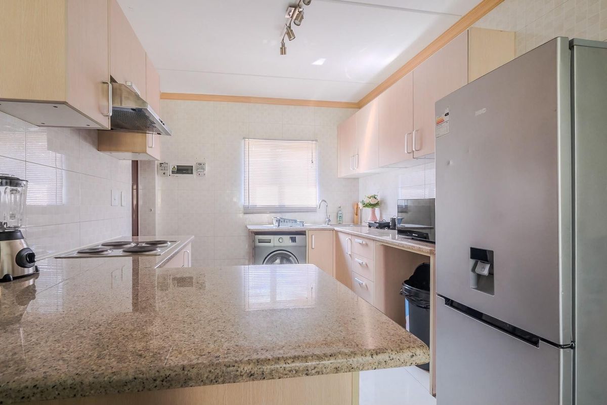 Functional kitchen featuring granite countertops, ample built-in cabinetry, a tiled backsplash, and integrated plumbing for laundry appliances.