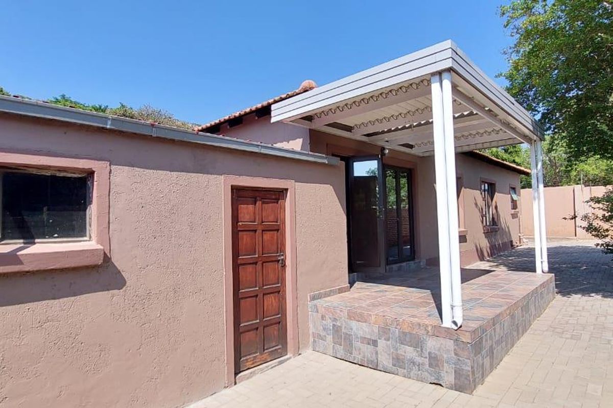 Rear exterior view of the townhouse featuring a covered patio area with tiled flooring and paved surrounding courtyard.