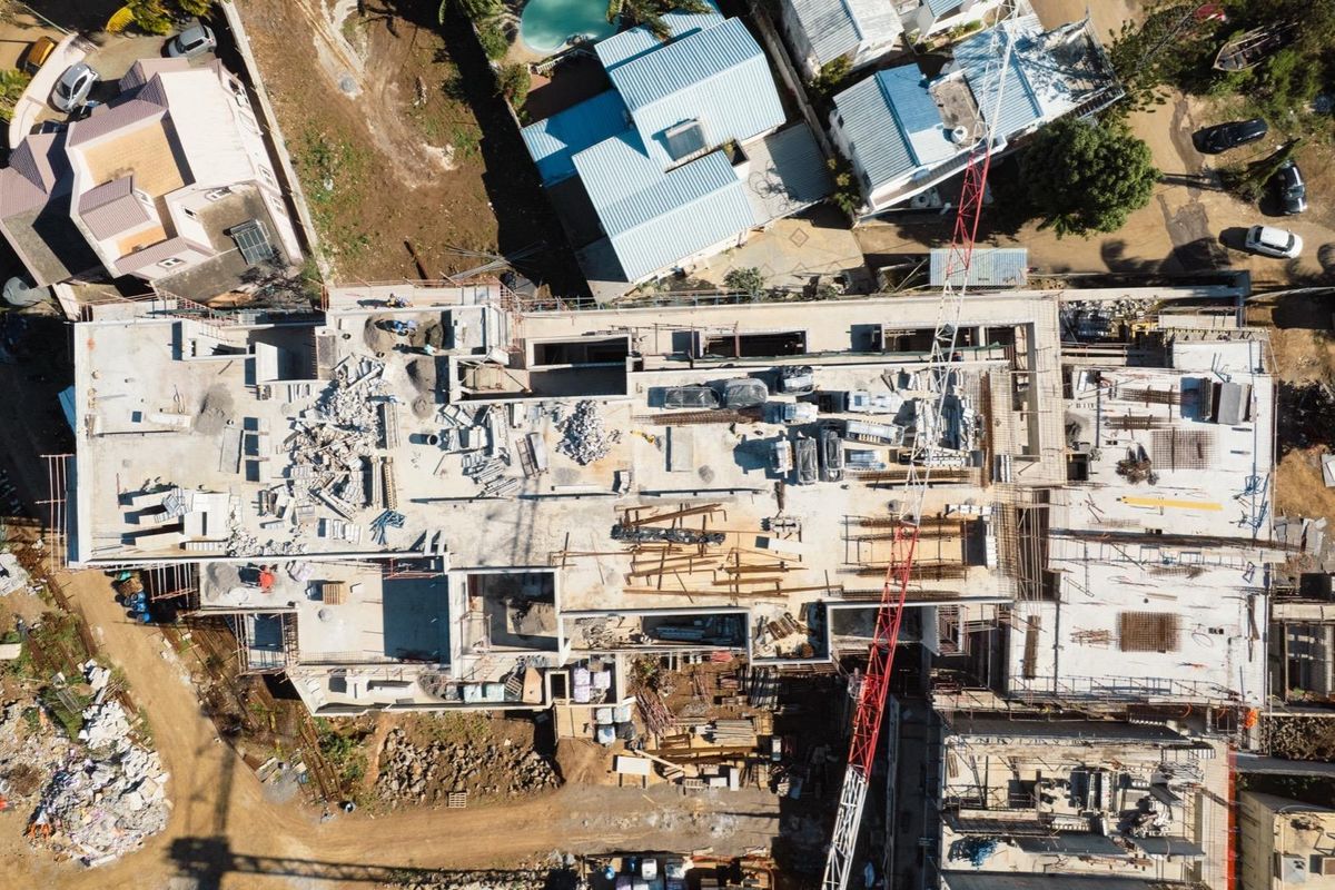 Aerial view of a penthouse construction site showing the concrete structural framework, ongoing building progress, and site equipment.