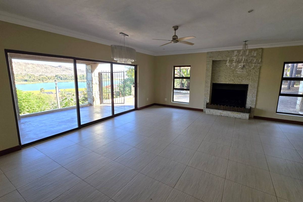 Spacious living room featuring large sliding glass doors with scenic views, a built-in stone fireplace, tiled flooring, and ceiling fans.
