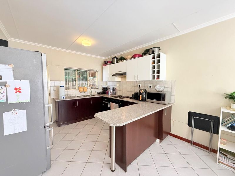 Functional kitchen featuring dark cabinetry, light countertops, tiled backsplash, and a breakfast bar peninsula, providing a practical layout for daily meal preparation.