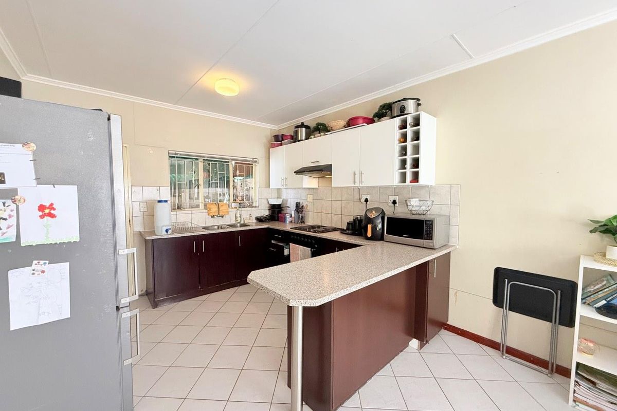 Functional kitchen featuring dark cabinetry, light countertops, tiled backsplash, and a breakfast bar peninsula, providing a practical layout for daily meal preparation.