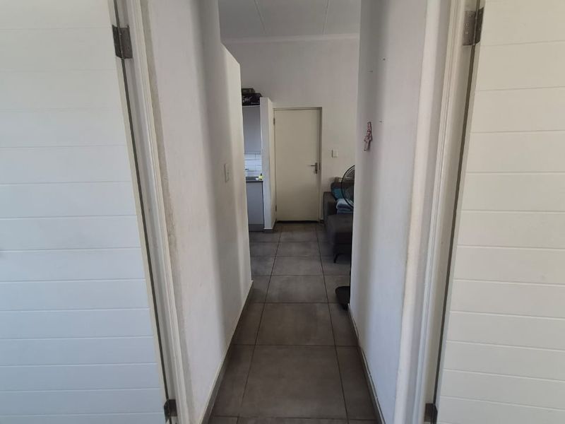 A functional hallway with tiled flooring connecting interior rooms, featuring white internal doors and neutral wall finishes.