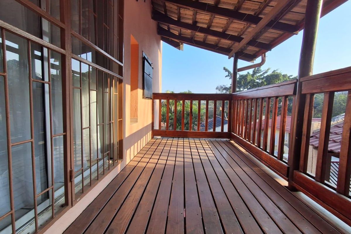 A covered timber balcony featuring wooden decking, a matching balustrade, and exposed roof rafters, offering an elevated outdoor space.
