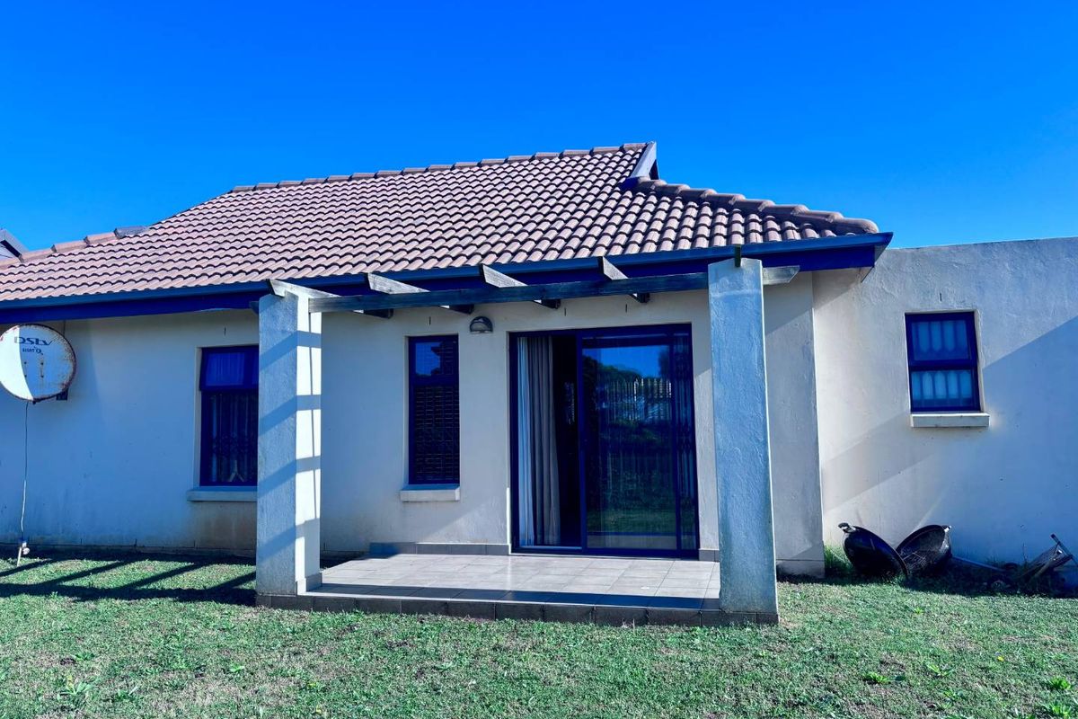 Rear exterior view of the townhouse featuring a tiled patio with a pergola, sliding glass doors, and a tiled roof.