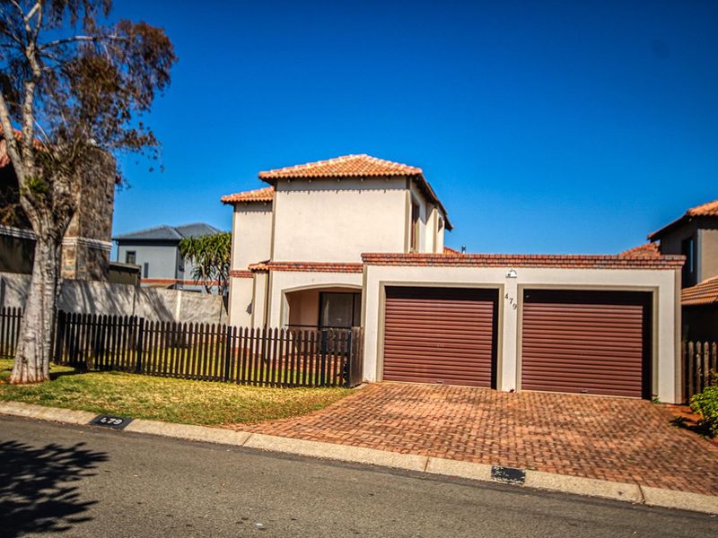 Front elevation of a two-story residential house featuring a double garage, paved driveway, and a fenced front garden area.
