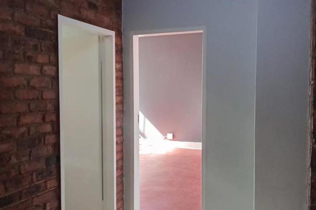 A functional hallway featuring an exposed brick wall, tiled flooring, and access to adjacent rooms.