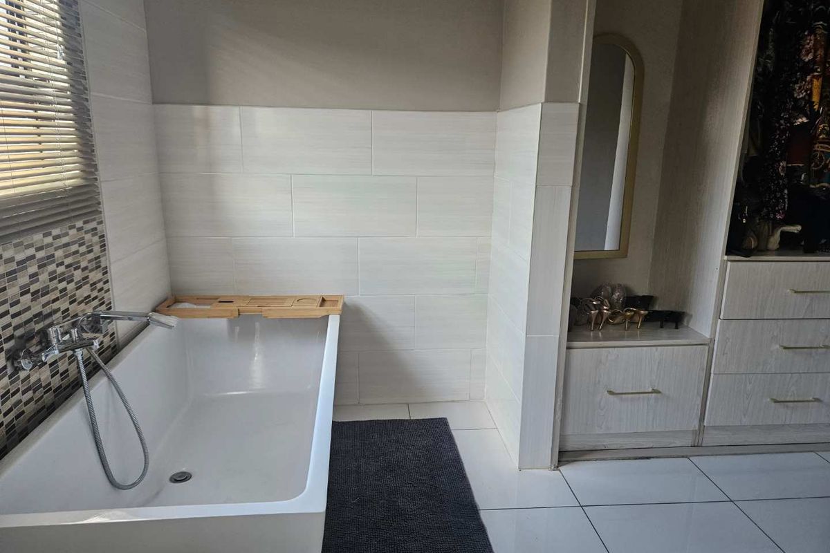 Modern bathroom featuring a sleek freestanding bathtub with wall-mounted fixtures, complemented by neutral wall tiling and integrated storage cabinetry.