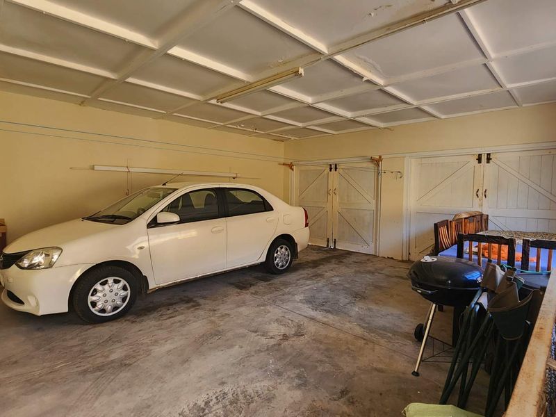 Spacious double garage featuring concrete flooring, functional lighting, and dual access doors, offering ample storage or parking space.