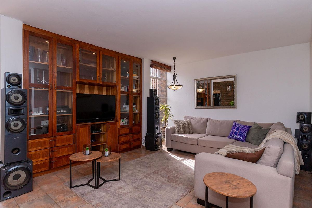 A comfortable living room featuring a large built-in wooden display cabinet and tiled flooring, providing a warm and functional space for relaxation.