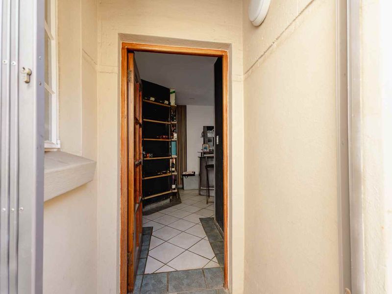 An entryway featuring tiled flooring and a security gate, leading into an interior space with built-in shelving.