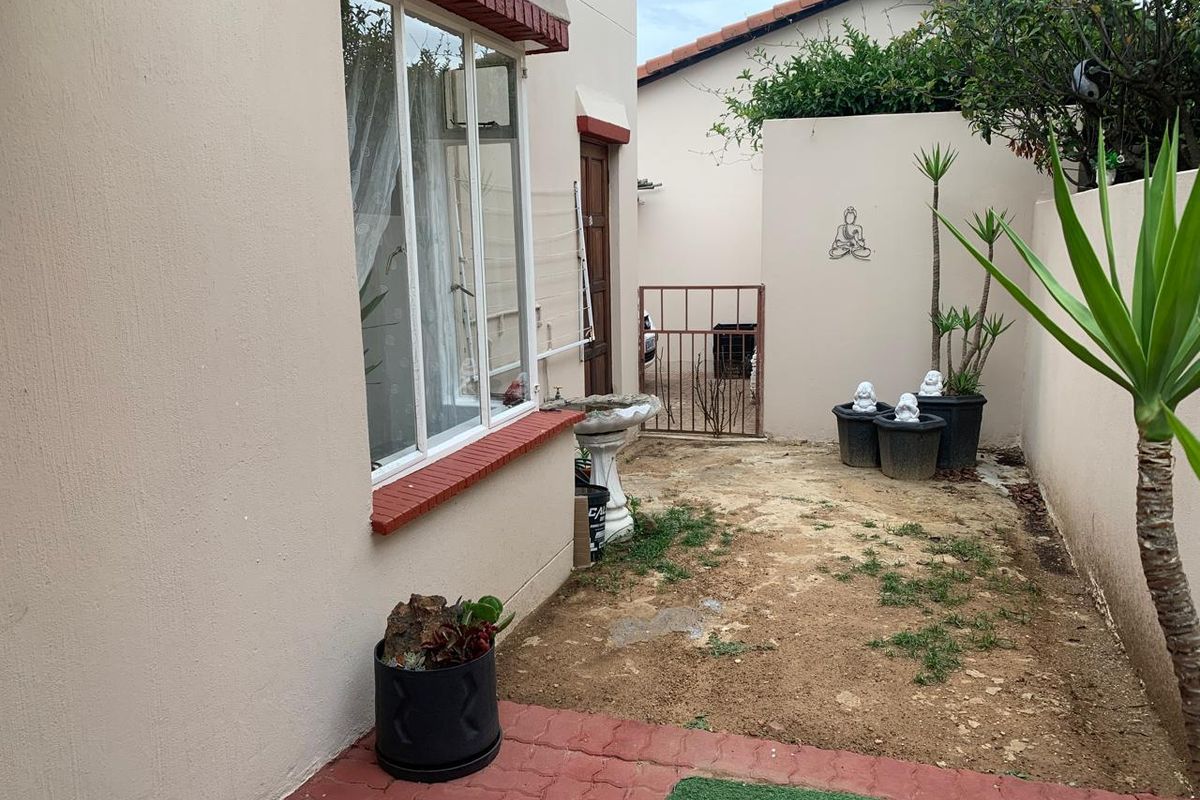 A small rear courtyard area featuring brick paving, a metal security gate, and boundary walls, requiring landscaping improvements to enhance the outdoor space.