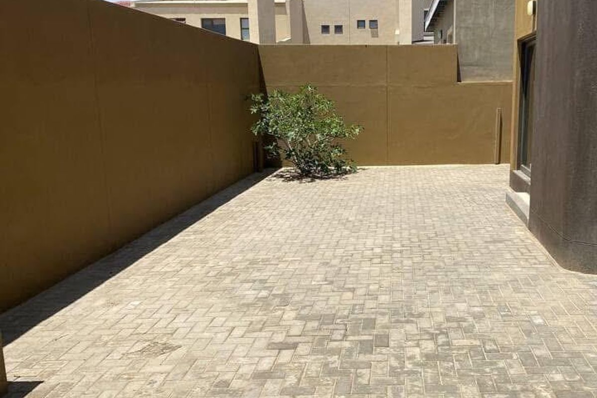 A private, paved rear courtyard area featuring high boundary walls and a low-maintenance outdoor space.