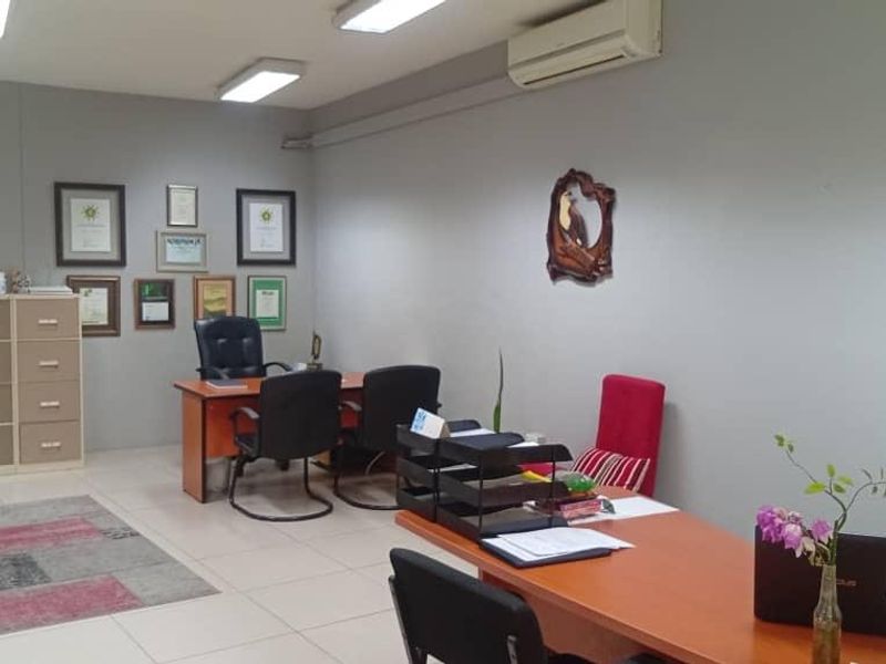 A functional office space featuring tiled flooring, overhead fluorescent lighting, and a wall-mounted split-system air conditioning unit.