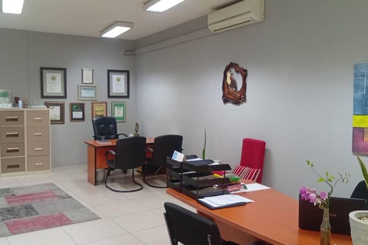 A functional office space featuring tiled flooring, overhead fluorescent lighting, and a wall-mounted split-system air conditioning unit.