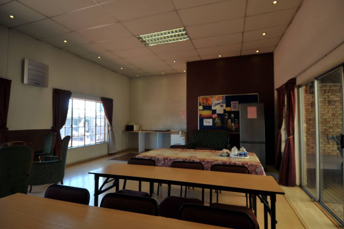 A spacious multi-purpose room featuring a drop ceiling with recessed lighting, large windows, and sliding glass doors leading to an outdoor area.