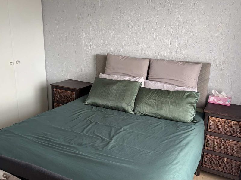 A functional bedroom featuring a built-in wardrobe with white doors and textured wall finishes.