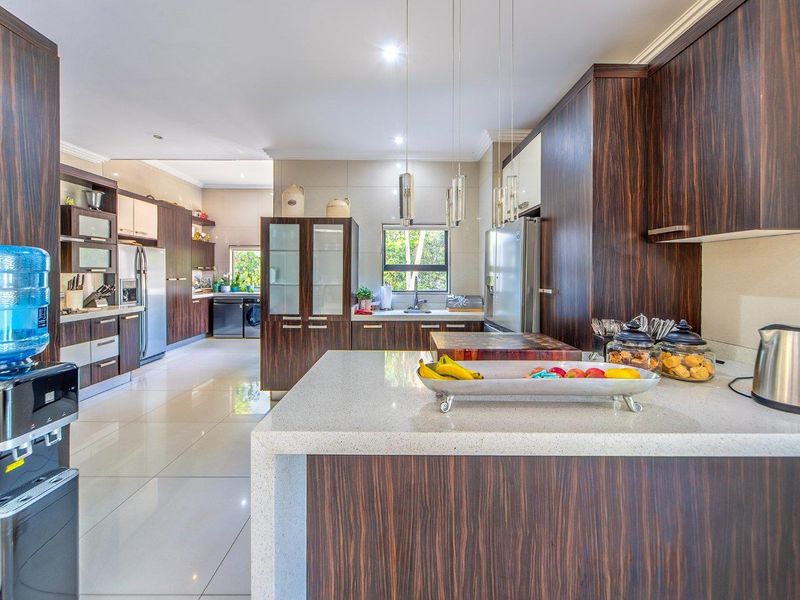 Modern kitchen featuring dark wood cabinetry, stone countertops, and a spacious layout with integrated appliances and high-quality finishes.