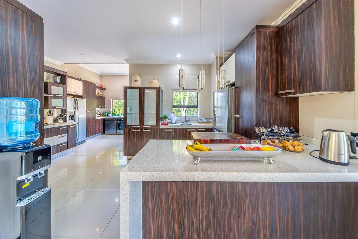 Modern kitchen featuring dark wood cabinetry, stone countertops, and a spacious layout with integrated appliances and high-quality finishes.