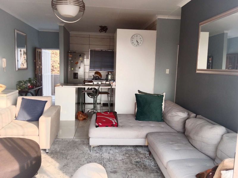 Open-plan living area featuring a breakfast bar, tiled flooring, and a compact kitchen space with neutral wall finishes.