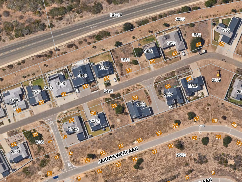 An aerial view of a residential estate showing multiple plots, paved streets, and existing housing developments.
