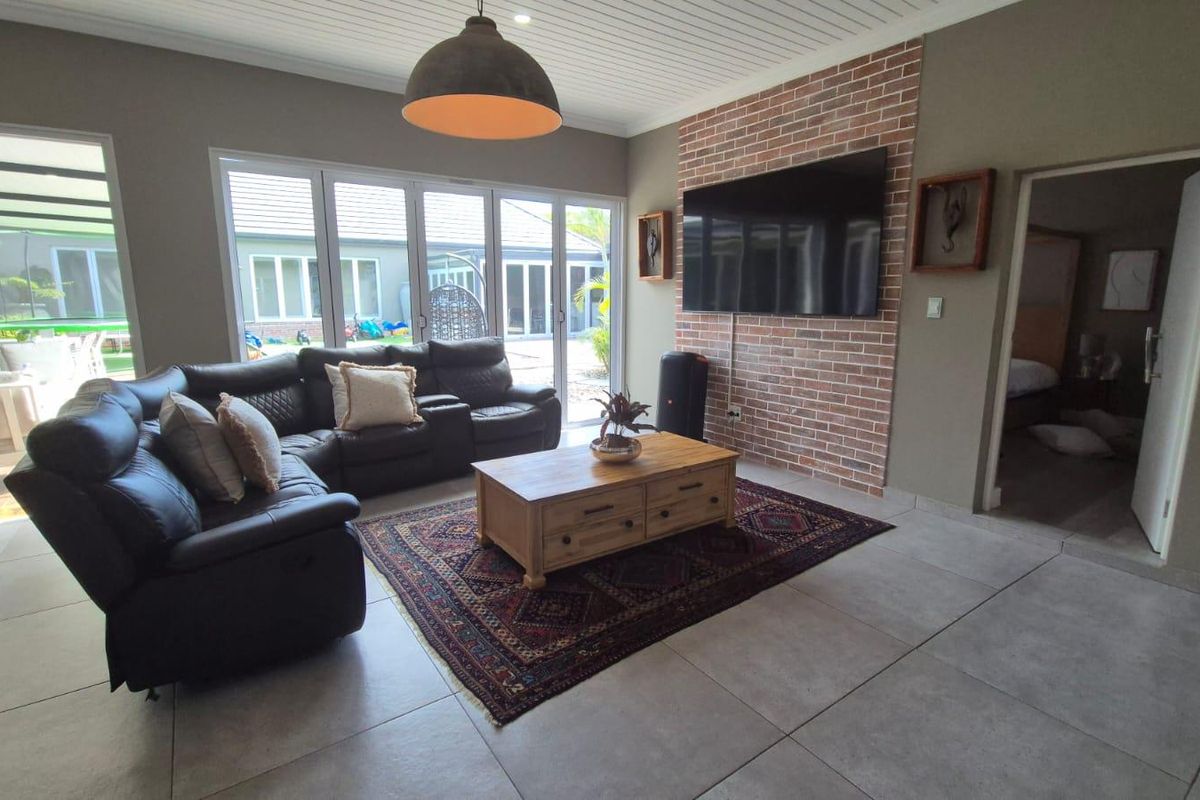 Spacious living room featuring a brick accent wall, large bi-fold doors providing natural light, and modern tiled flooring.