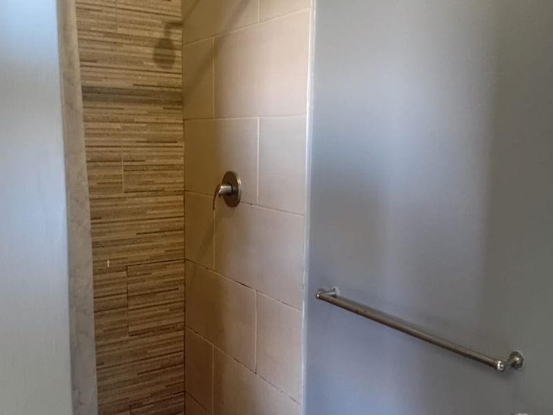 A functional bathroom shower area featuring a pebble floor, tiled walls, and a modern shower mixer fixture.