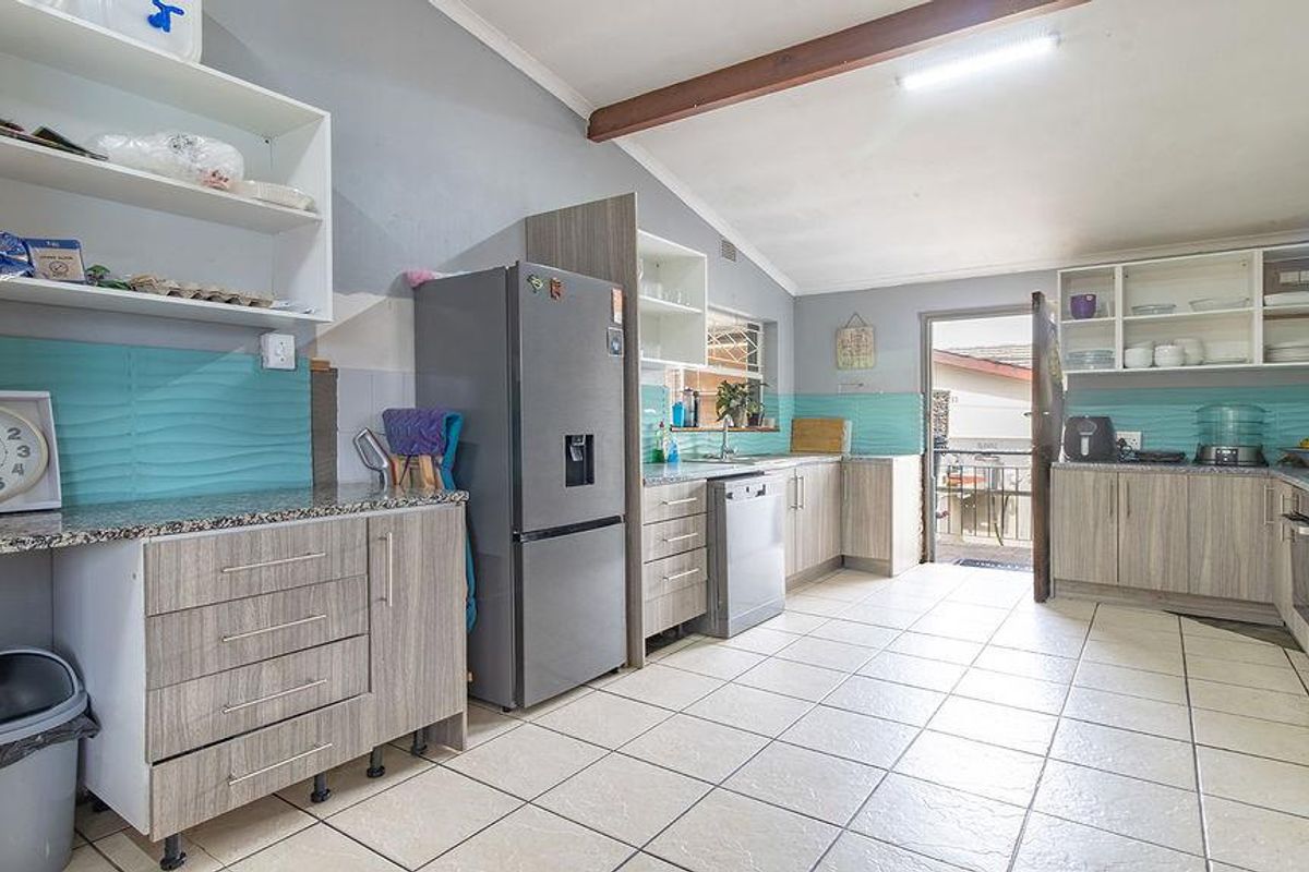 Functional kitchen featuring wood-look cabinetry, granite countertops, a tiled backsplash, and direct access to the exterior.