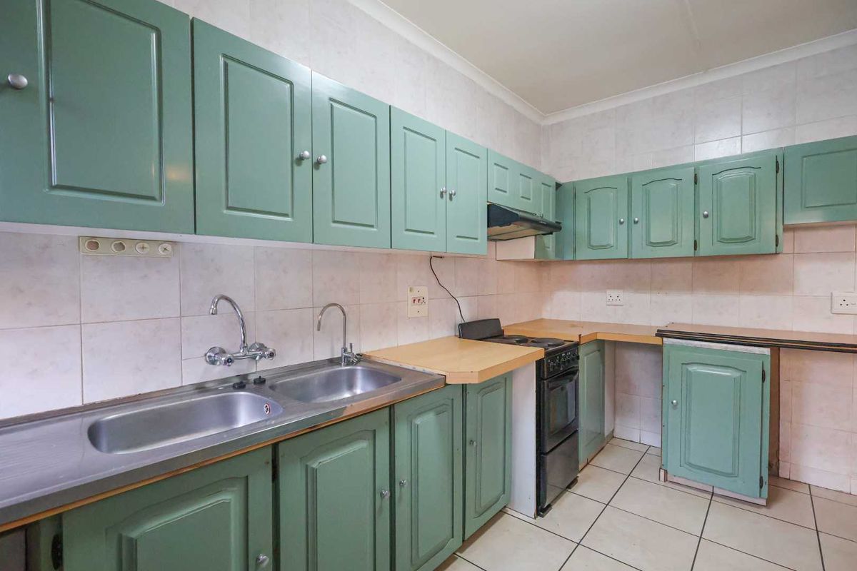 A functional kitchen featuring green cabinetry, a double stainless steel sink, tiled backsplash, and a built-in stove with an extractor fan.