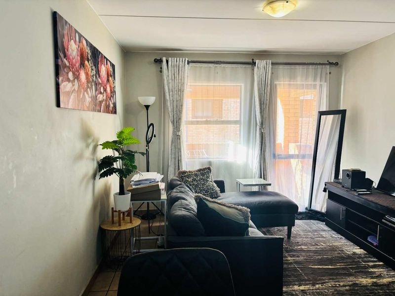 A comfortable living room featuring tiled flooring and a sliding glass door that provides natural light and access to the exterior.