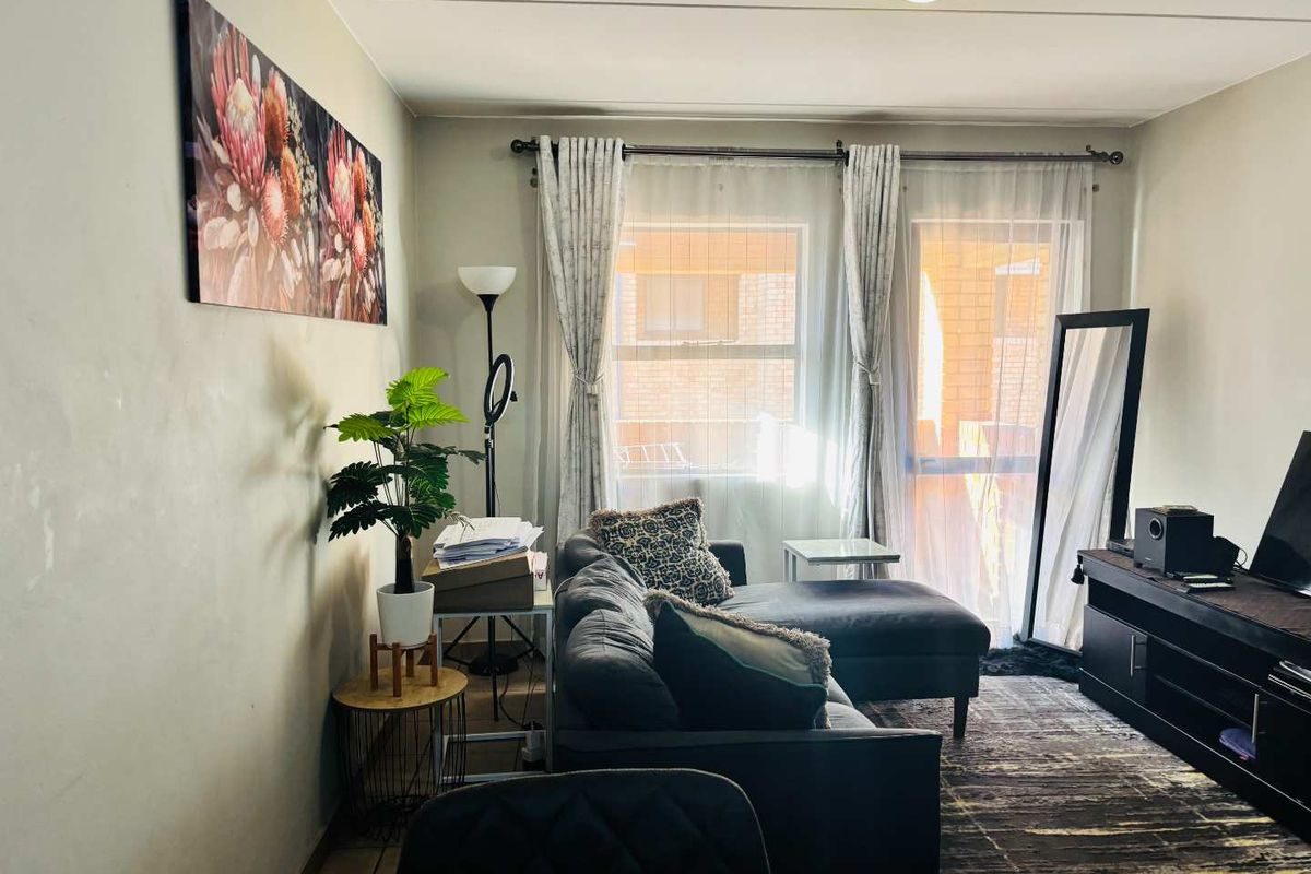 A comfortable living room featuring tiled flooring and a sliding glass door that provides natural light and access to the exterior.