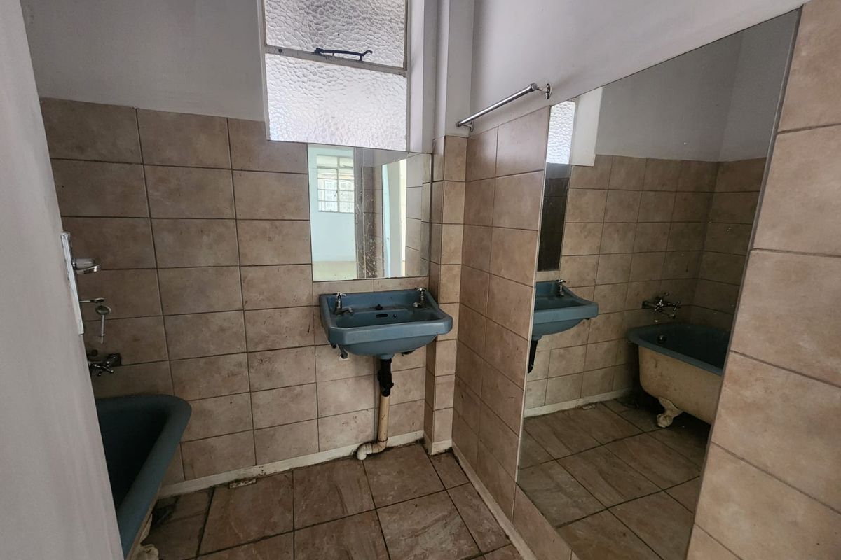 A dated bathroom featuring a vintage clawfoot bathtub, wall-mounted basin, and tiled finishes, requiring modernization to improve functionality and aesthetic appeal.